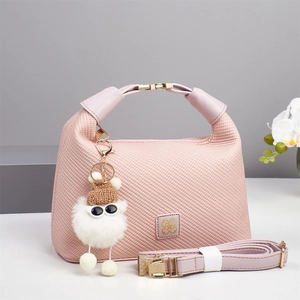 Pink woven texture mini pillow bag with golden clover logo and plush monster charm