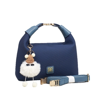 Navy blue woven hobo bag with gold floral logo and cute plush monster charm