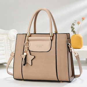 Détail du sac cabas en toile avec breloque étoile, logo en métal et bandoulière