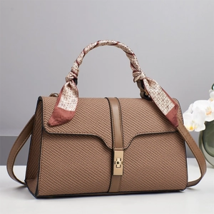 Dettaglio borsa a mano in pelle marrone intrecciata con foulard e fibbia in metallo oro
