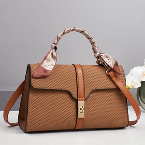 Dettaglio della borsa intrecciata marrone con chiusura dorata e sciarpa di seta decorativa