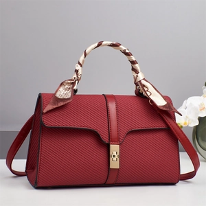 Dettaglio della borsa a tracolla rossa con trama intrecciata e foulard in seta sul manico