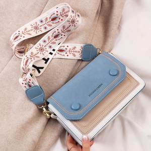 Chic tricolor square crossbody bag with wide patterned strap on soft textured background