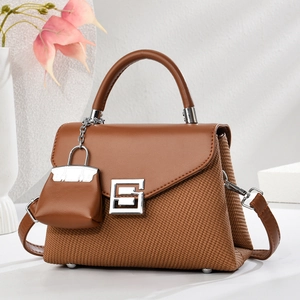 Detail view of the brown leather texture and woven fabric material on the handbag