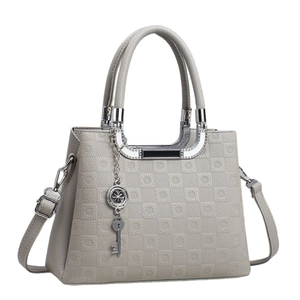 Sac à main beige gaufré avec poignées métalliques et pendentif trèfle élégant