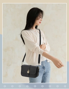 Détail du sac bandoulière en cuir noir avec une élégante boucle ronde en métal doré