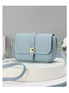 Détail du sac à bandoulière en cuir bleu clair avec fermoir doré et texture litchi