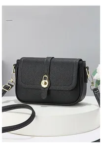 Détail du sac selle en cuir grainé noir avec surpiqûres blanches contrastées et boucle dorée