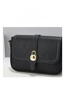 Détail du sac à main noir en cuir grainé avec surpiqûres blanches et boucle dorée