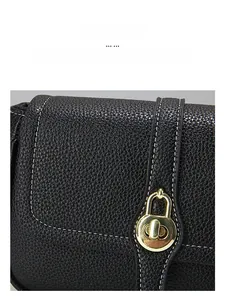 Gros plan détaillé du sac en cuir noir avec fermoir doré rotatif et surpiqûres blanches