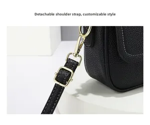 Détail d'un sac en cuir noir grainé avec boucles dorées et bandoulière amovible