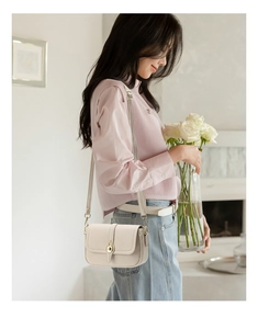 Détail du sac bandoulière abricot avec fermoir doré et cuir à texture grainée