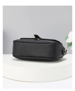 Détail de la texture du cuir grainé noir et des ferrures dorées sur le sac à bandoulière