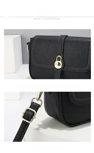 Détail du sac à main en cuir grainé noir avec boucle dorée et surpiqûres blanches