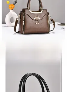 Detail of lychee pattern leather handbag handle with swan charm and golden hardware