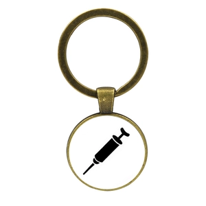 Macro detail of bronze alloy keychain featuring a glass cabochon with syringe medical icon