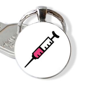 Close-up of metal keychain with syringe illustration and silver key accessory