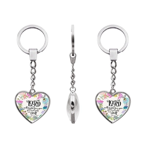 Macro view of heart pendant keychain with religious quote and floral pattern detail