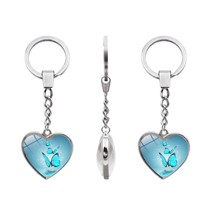 Detail of three heart-shaped keychains with blue butterfly designs in silver frames