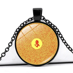 Macro shot of circular glass pendant with spiral mantra scripture and red Sanskrit character
