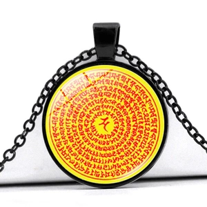 Macro view of a black round pendant necklace featuring religious Sanskrit symbols