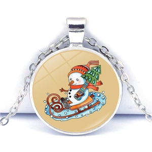 Vue macro du pendentif en verre argenté avec illustration de bonhomme de neige et sapin