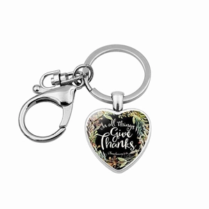 Detail of heart pendant keychain with In all things Give thanks text and floral wreath