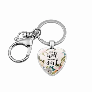 Detail of silver heart keychain with floral print and It is well with my soul text