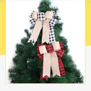 Detail of red black plaid and linen bow ornament on a green Christmas tree top