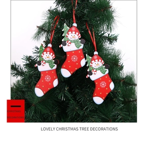 Detailed view of three red wooden Christmas stocking pendants with cute snowmen on a tree