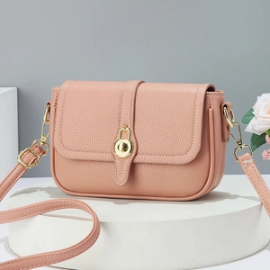 Sac à bandoulière en cuir rose grainé avec fermoir rotatif doré sur socle blanc