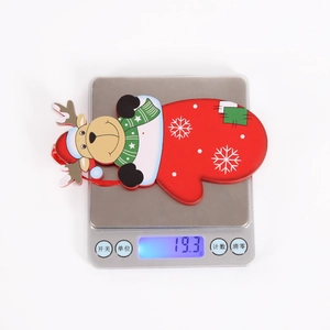 Detailed close-up of a red glove Christmas ornament with reindeer motif on a weight scale