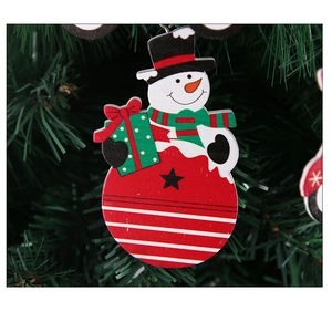 Detail eines hölzernen Weihnachts-Schneemann-Anhängers mit Geschenkbox am Tannenbaum