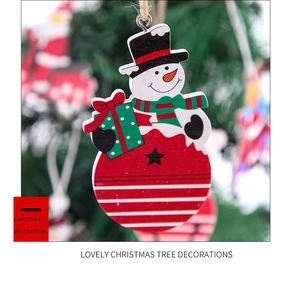 Detail eines festlichen Holzschneemann-Anhängers mit grüner Geschenkbox und rotem Hut