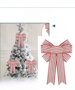 Close-up of red and white striped Christmas bow hanging on a white decorative tree branch