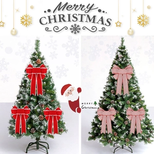 Large red velvet and striped Christmas bows decorated with faux pine and snow on a tree