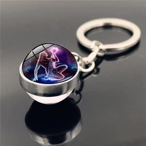Close-up of double-sided glass ball keychain with glowing purple Aquarius zodiac theme