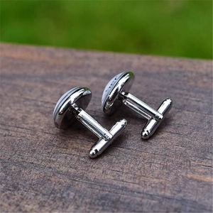 Silver round cufflinks with Africa and Europe map design on dark wood surface