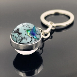 Close-up of hummingbird glass dome keychain with colorful floral patterns and silver ring