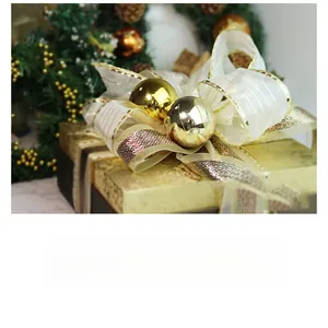 Detalle de caja de regalo oro champán con lazo grande de cinta crema y rayas oro