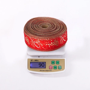 Macro shot of 90g red Christmas ribbon with gold Merry Christmas print on scales