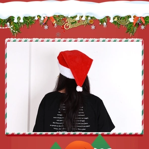 Back view of a model wearing a plush red Christmas hat with white pom-pom and festive border