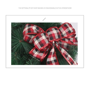 Detail of red and black plaid Christmas bow with red glitter edges on a pine branch