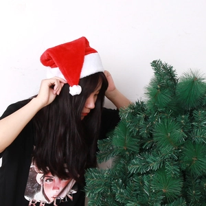 Classic red plush Christmas hat with white fur trim and pompom worn by a model