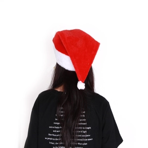Classic red plush Christmas hat with white pompom worn by a person on white background