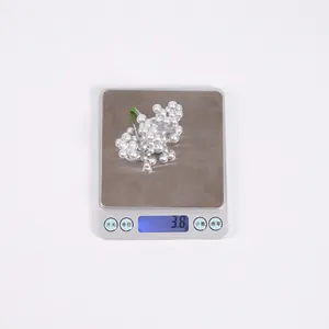 Détail d'un ornement de Noël en perles blanches pesant 3,8 g sur une balance