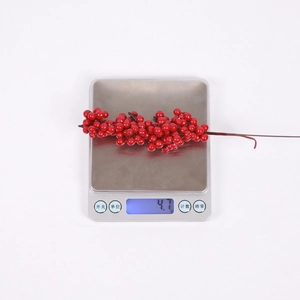 Dettaglio di un ramo di bacche rosse artificiali su una bilancia del peso di 4,7 grammi