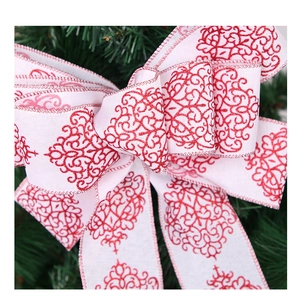 Detail der roten Glitzer-Schnörkel auf weißer Weihnachtsschleife für den Tannenbaum