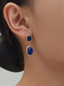 Detail of vintage geometric 18k gold plated earrings with faceted blue glass stones