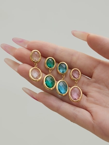 Detail of colorful oval faceted glass stone earrings with 18k gold plated geometric settings